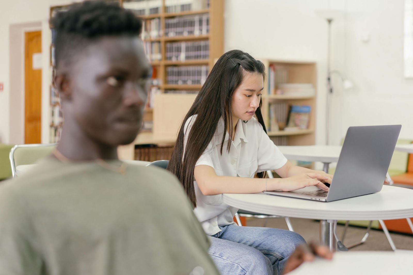 A student works on her laptop in the background of a classroom.