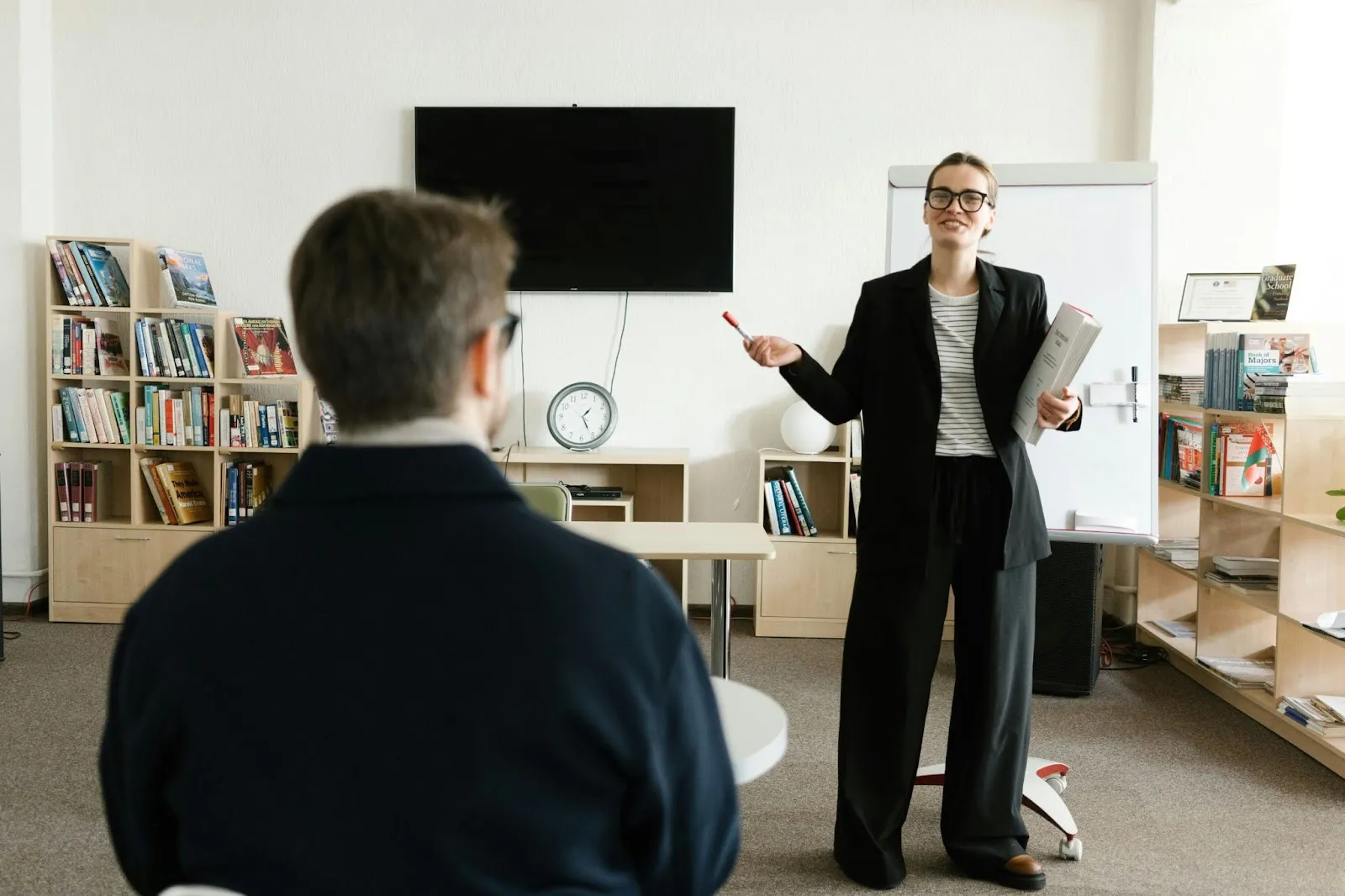 A female administraor speaks emphatically to her audience of one in a modern school classroom.