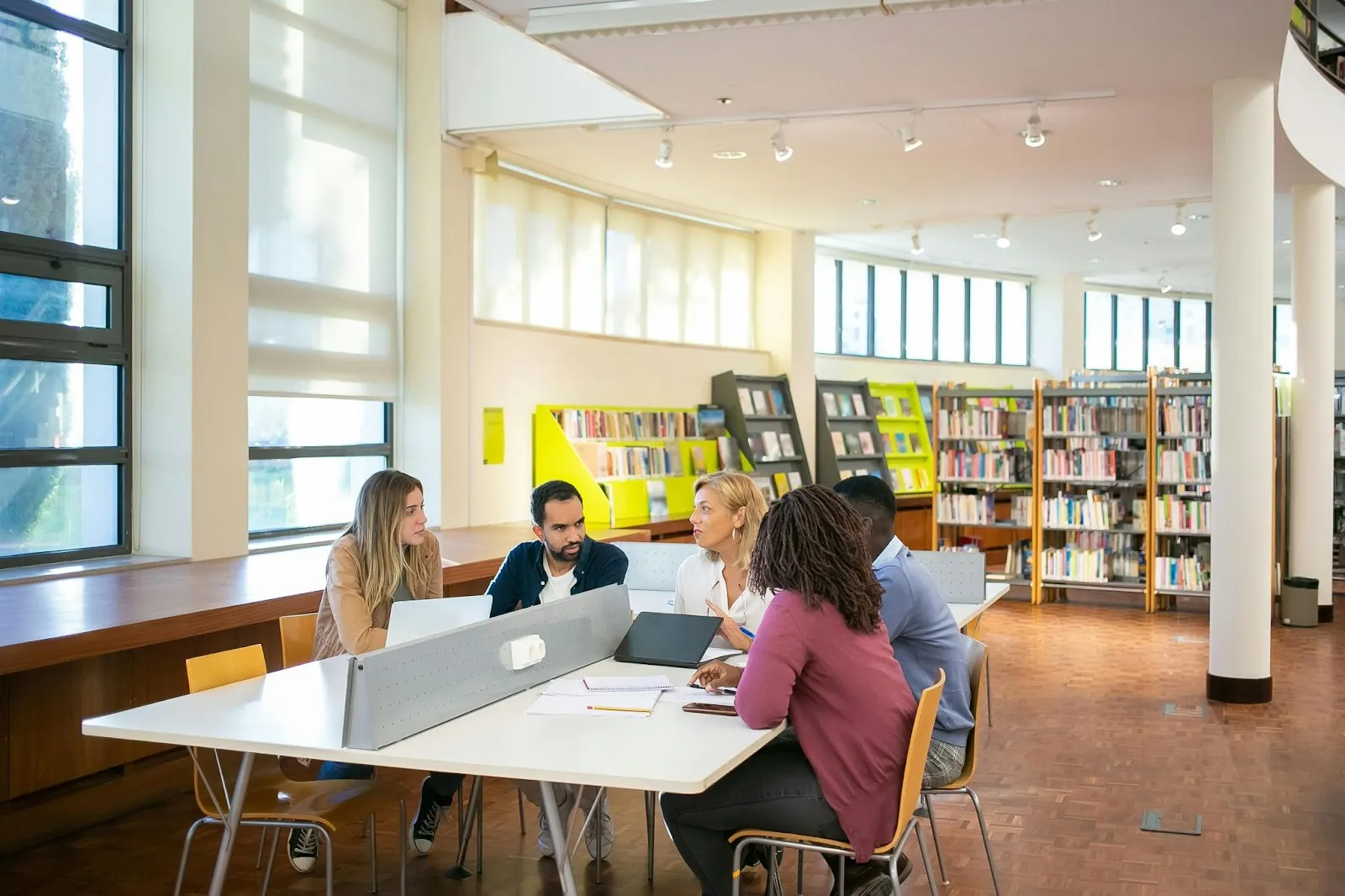 A group of teachers gather in the library for a discussion.