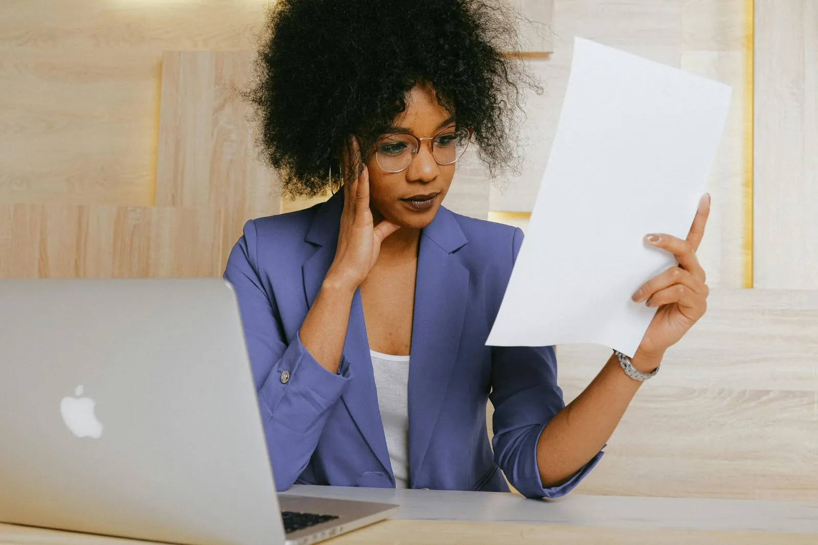 An administrator looks over a document with her laptop open in front of her.