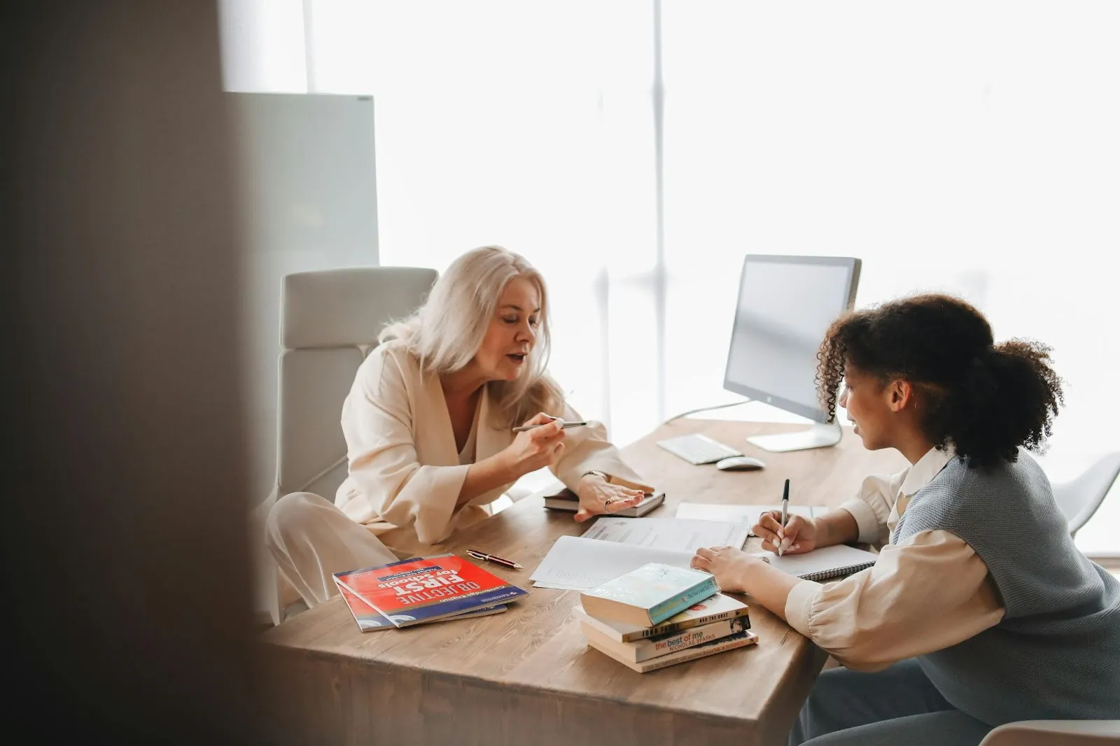 A teacher works with her student over a workbook