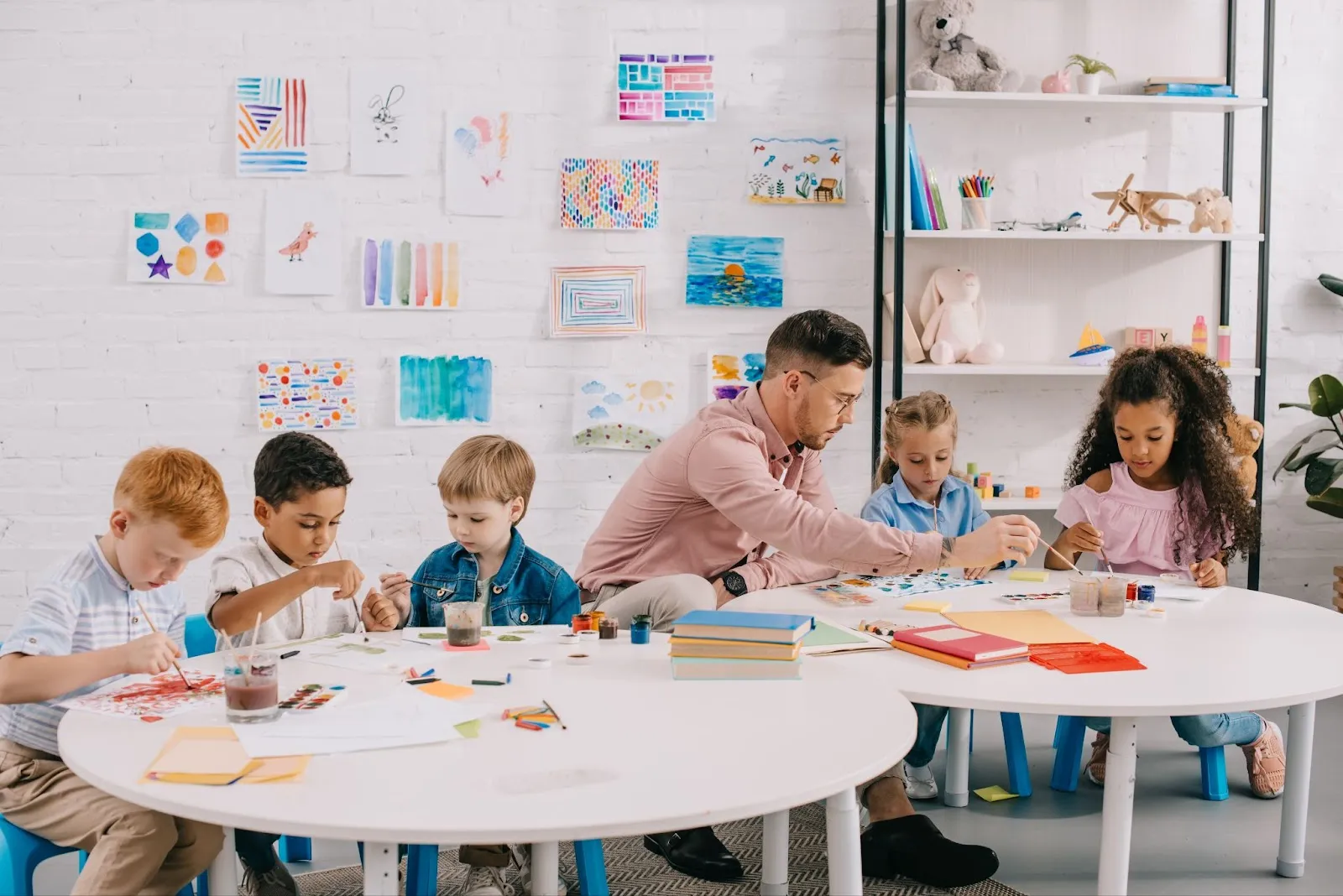 A teacher works between two groups of students at their tables.