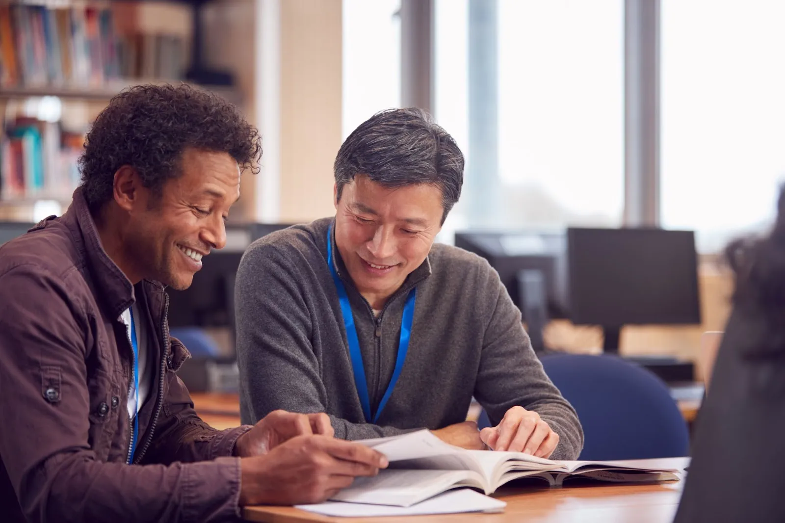 Two teachers share a booklet.