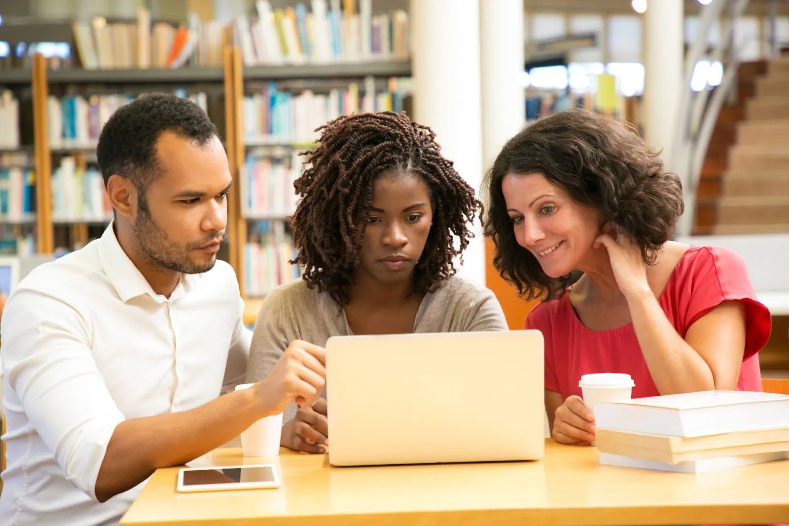 Three teachers huddle around a laptop to look at data.