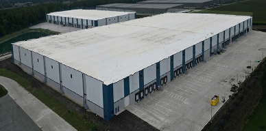 Black and white photo of a large, vintage factory interior with workers operating machinery and equipment.