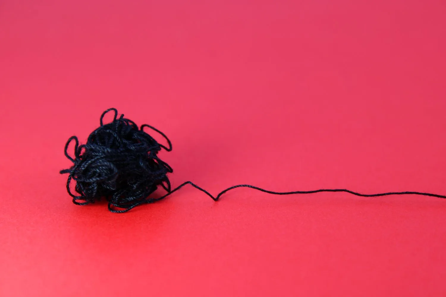 Close-up of a tangled thread with one clear line coming out of the knot, symbolising clarity, direction, and trust in times of uncertainty.