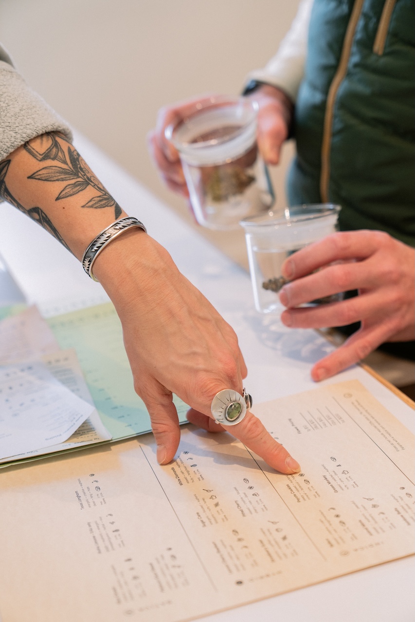 Juniper Cannabis budtender pointing to cannabis product details inside Juniper Dispensary