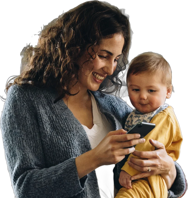 Smiling mother holding her baby while checking her phone