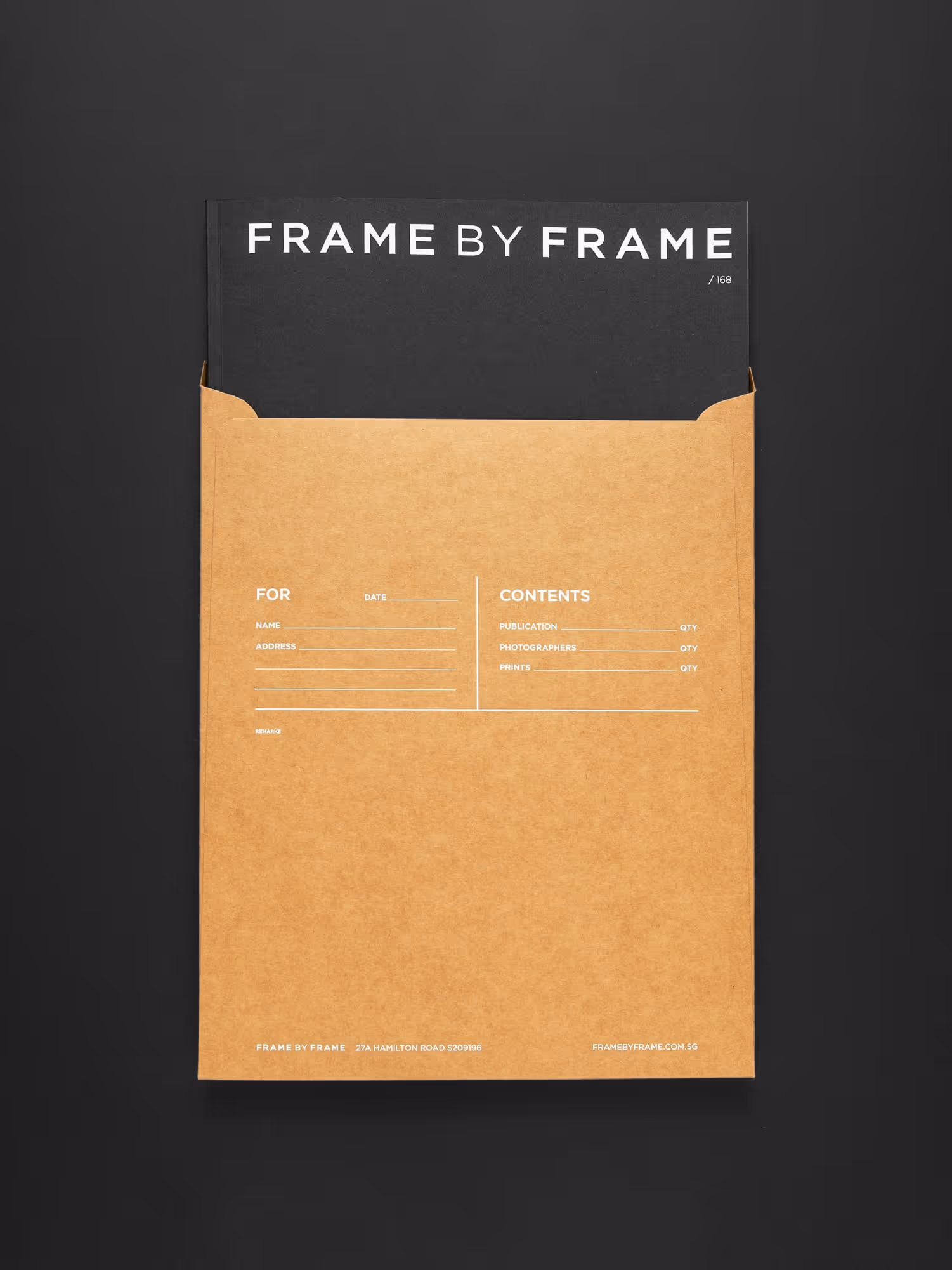 Black booklet titled 'FRAME BY FRAME' partially inside a brown envelope with printed form fields for name, address, contents, and dates on a black background.
