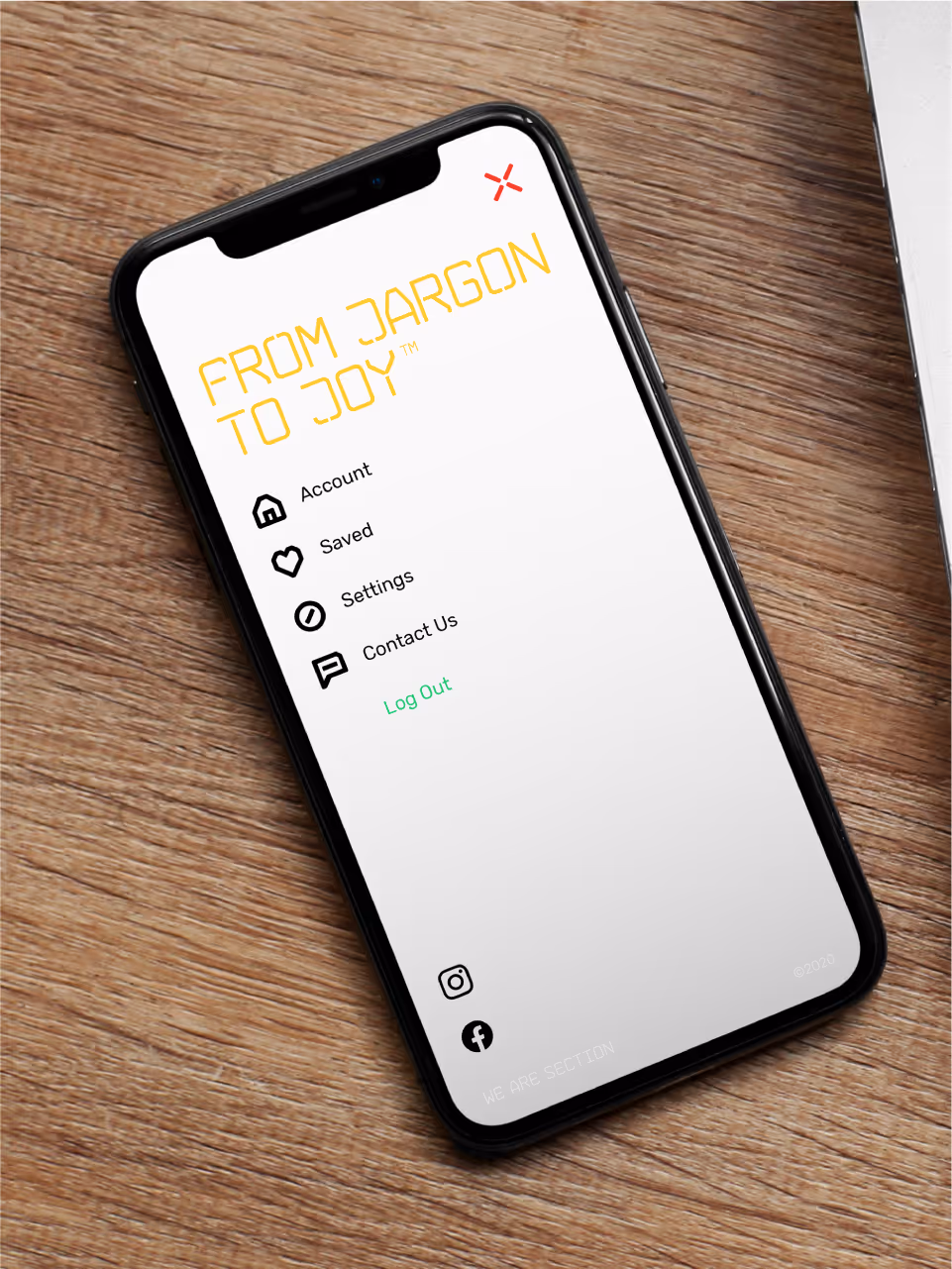 Smartphone on wooden surface showing app menu screen titled 'FROM JARGON TO JOY' with icons for Account, Saved, Settings, Contact Us, Log Out, and social media links.