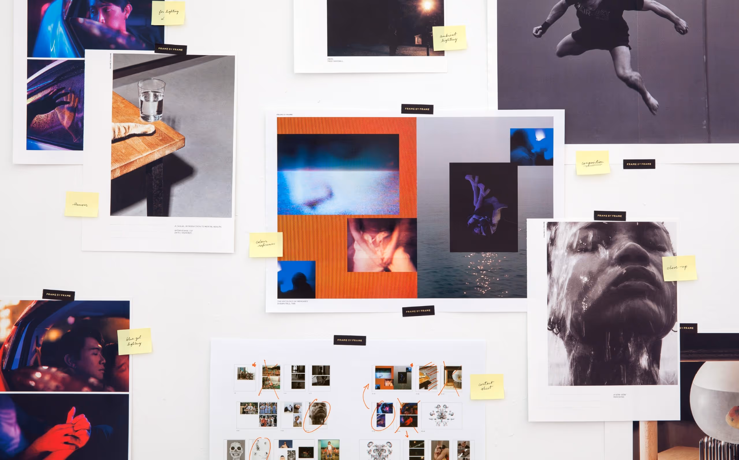 Wall displaying multiple artistic photographs with handwritten yellow sticky notes annotating themes like lighting, color, and composition.