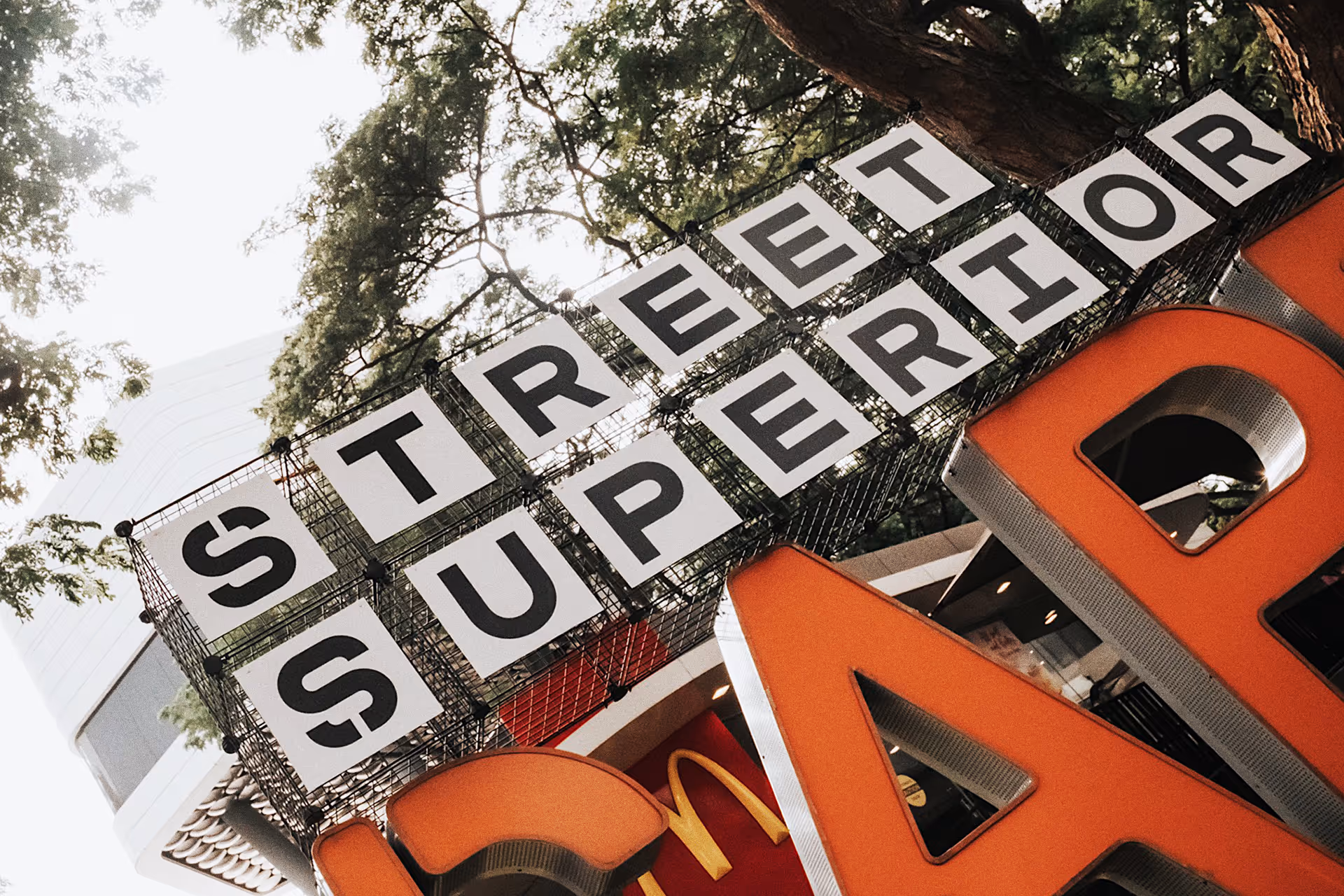Outdoor sign reading 'STREET SUPERIOR' with large orange letters partially visible below and trees in the background.