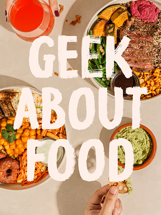 Overhead view of two bowls with grilled vegetables, chickpeas, steak, and greens, with dip and a hand holding a cracker, overlayed by text 'Geek About Food'.