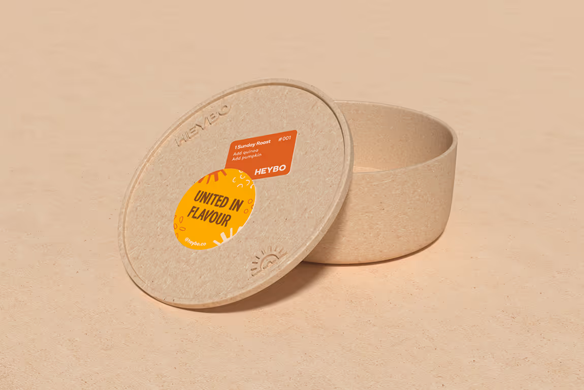 Open beige textured container with an embossed lid featuring colorful labels reading 'United in Flavour' and 'Sunday Roast' on a matching beige surface.