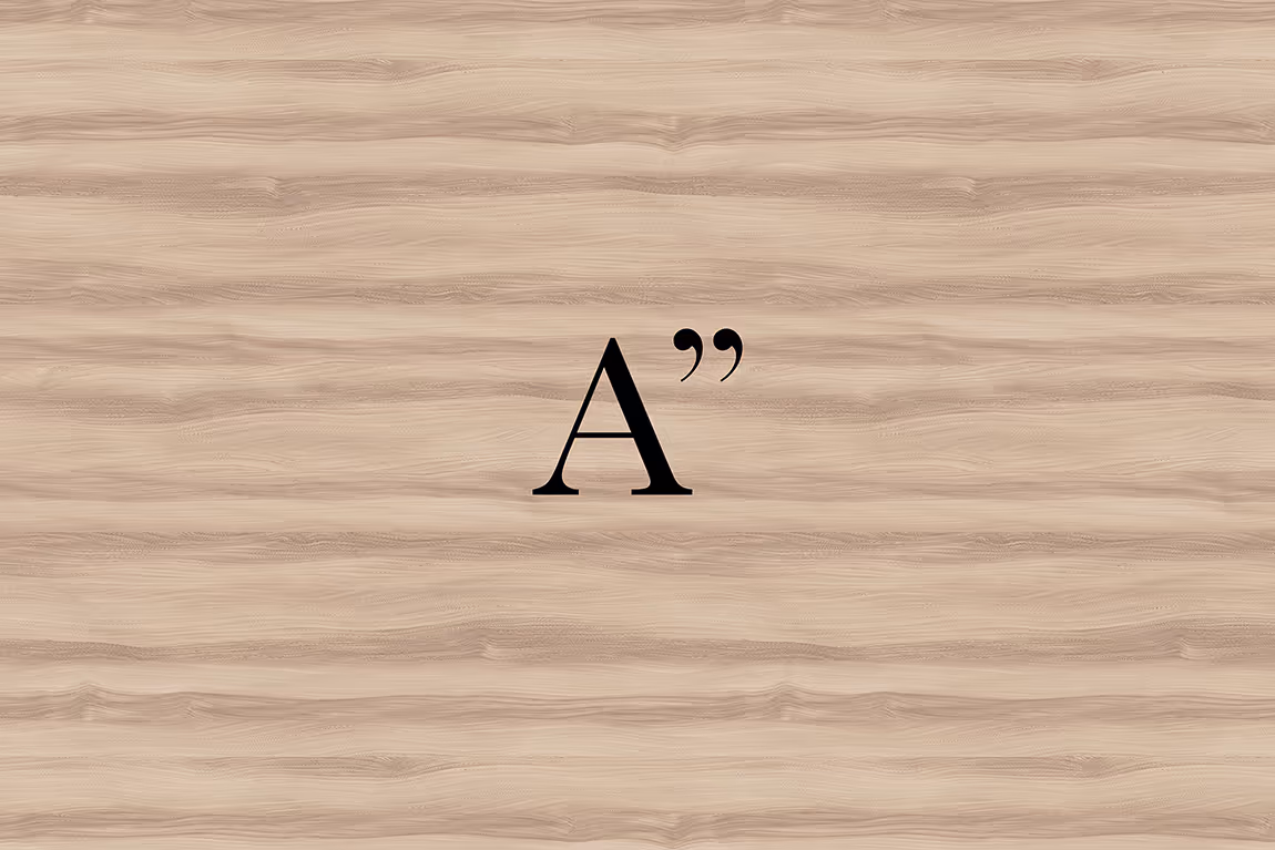 Black letter A followed by closing double quotation marks on a light wood grain background.