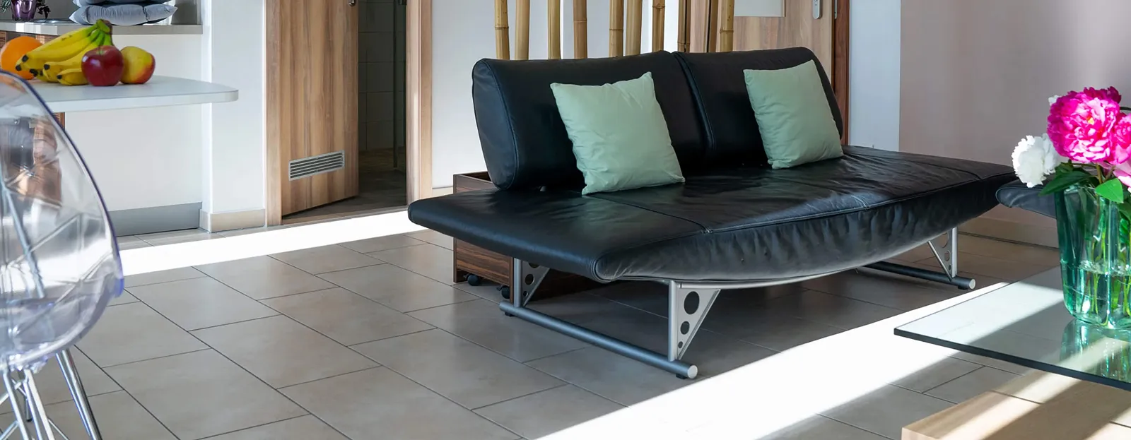 A black leather couch sitting in a living room next to a glass table.