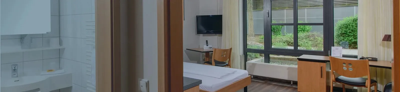 A room with a bed, desk, and a tv.