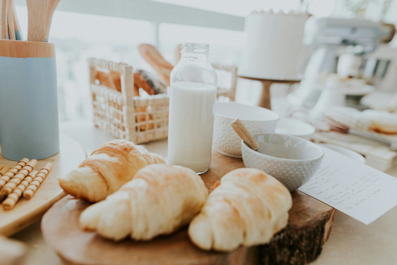 A table topped with croissants and a bottle of milk.