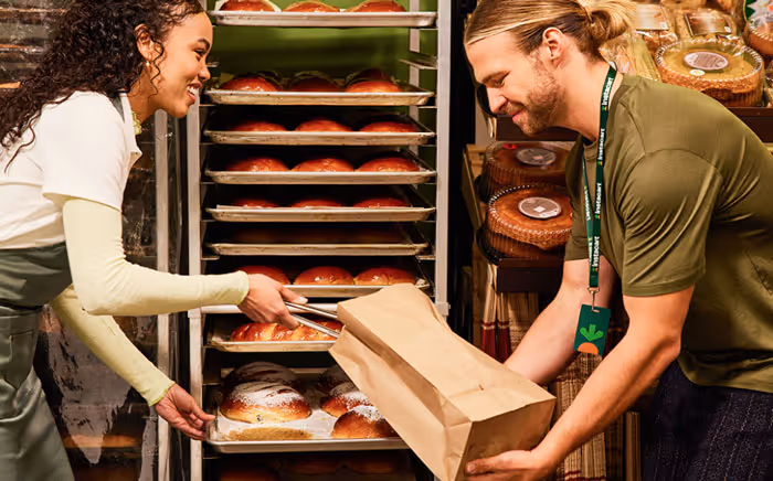 a woman bakery worker placing baked goods into a bag held by a man Instacart shopper