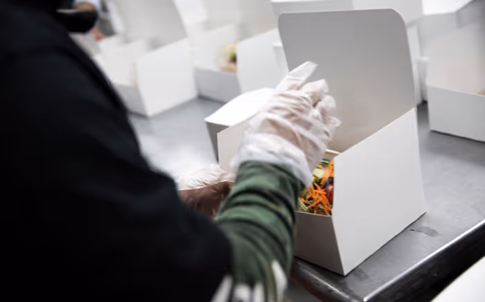 kitchen worker placing catering orders into boxes