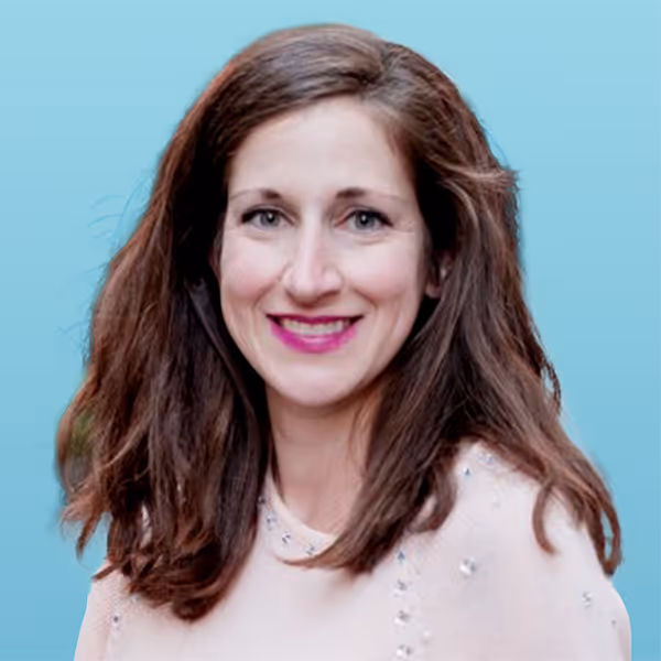 Smiling woman with long brown hair and bright pink lipstick against a light blue background.