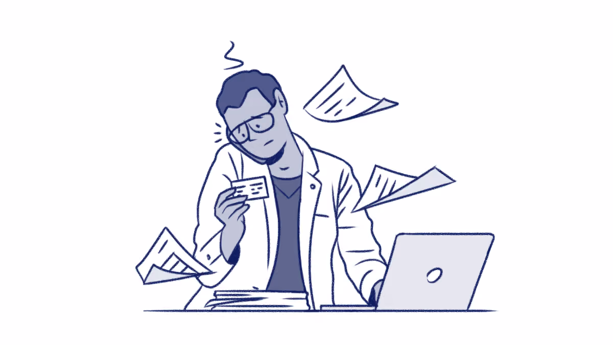 Stressed man with glasses holding a card, surrounded by flying papers and working on a laptop.