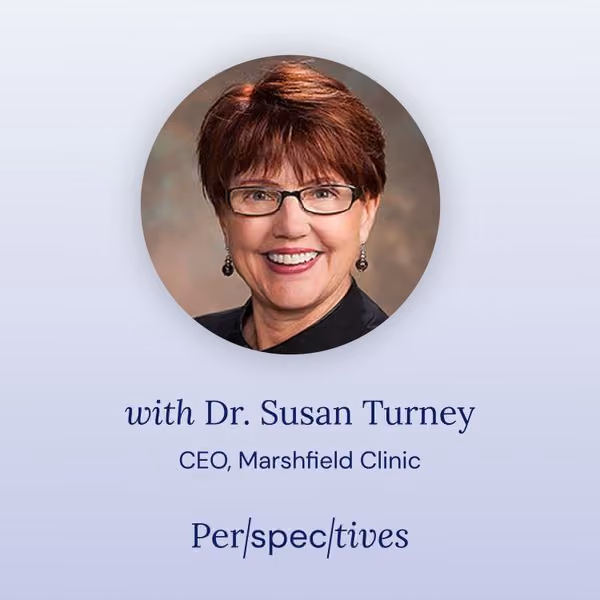 Portrait of Dr. Susan Turney, CEO of Marshfield Clinic, smiling with short reddish hair and glasses.