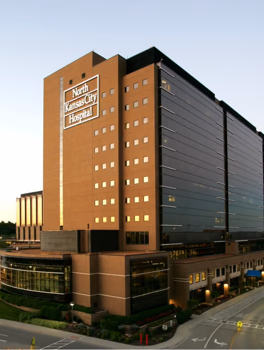 Large North Kansas City Hospital building with glass windows and brick exterior at dusk.