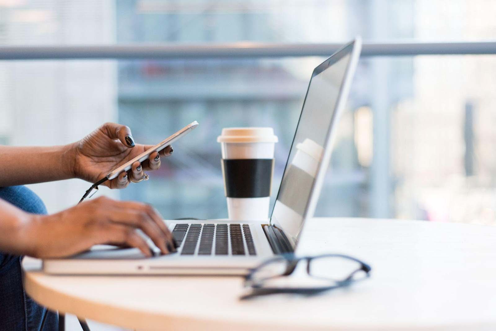 A woman hard at work on her laptop with a coffee.