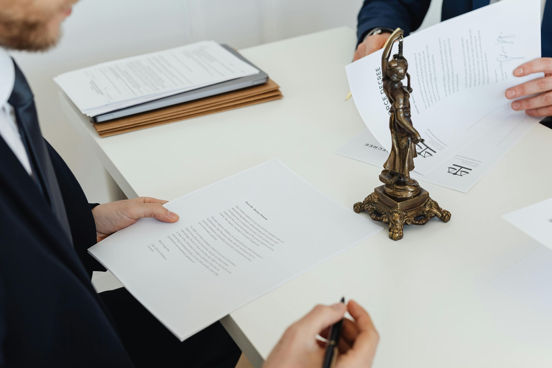Lawyers reviewing legal documents with Lady Justice statue on table