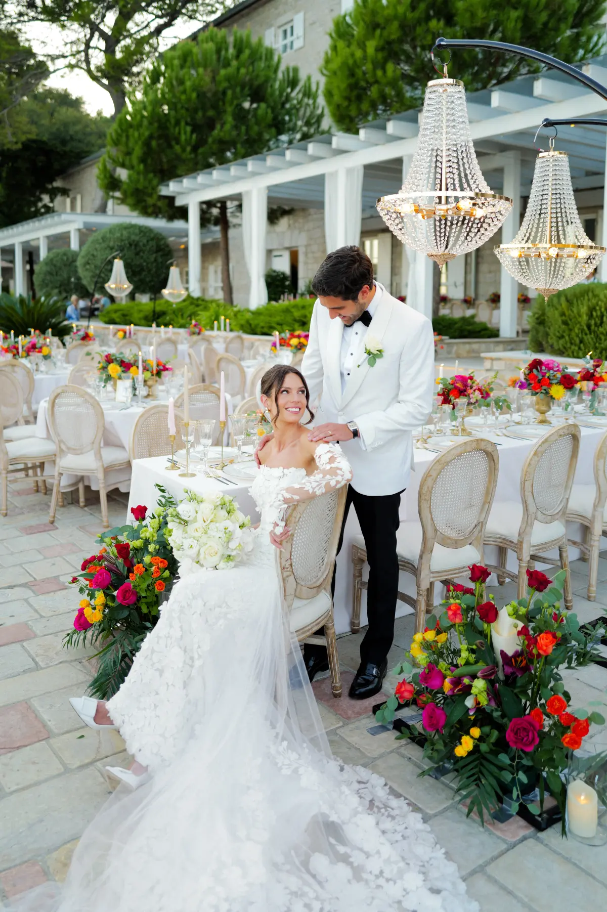 A woman on a white dress sitting on a bench while fixing her shoe
