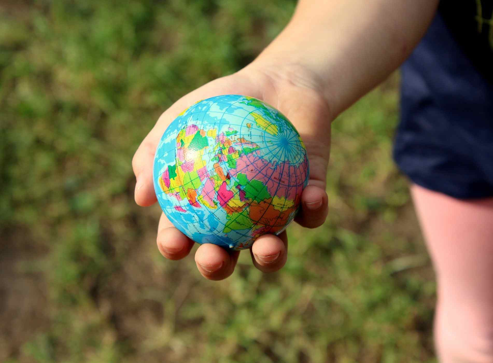 Kinderhand hält einen kleinen Globus 