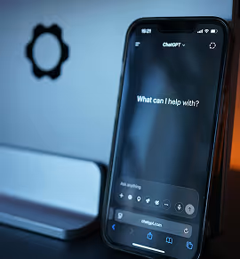 Smartphone displaying ChatGPT app with the prompt 'What can I help with?' on the screen.