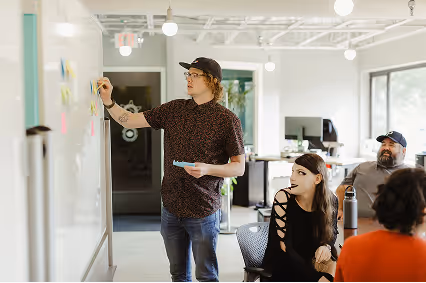 An Atomic team collaborates in a modern office setting, discussing AI software development and project planning.