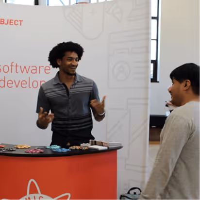 Atomic Object team member engaging with a visitor at a recruitment event, promoting software development services.
