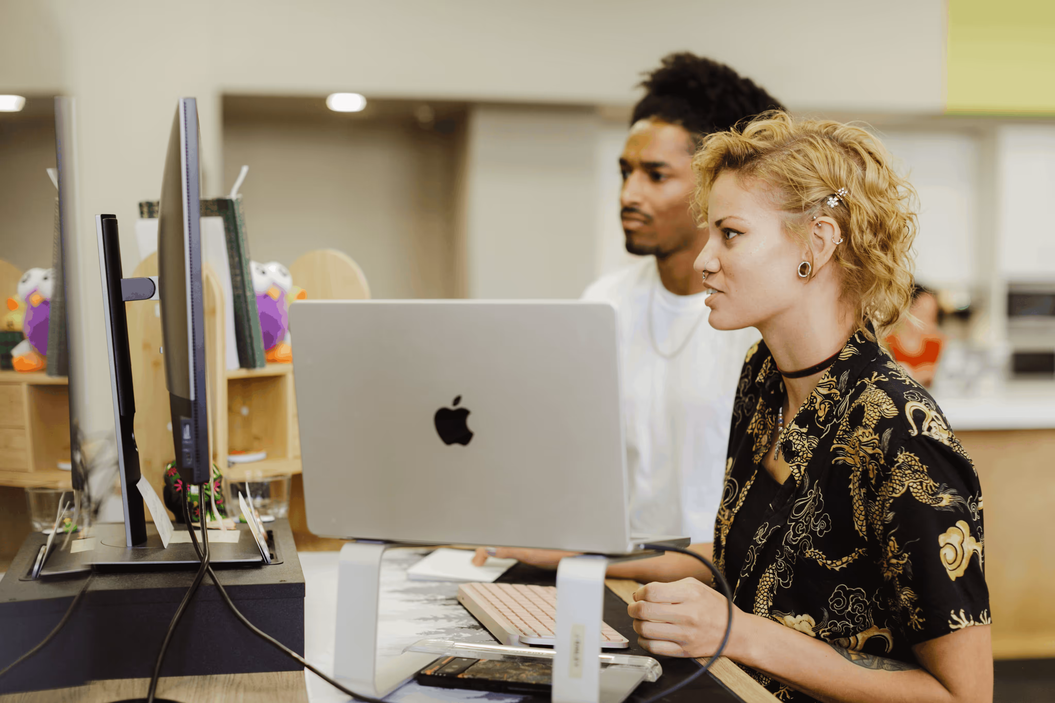 Atomic Object team collaborating on a project at a workstation with computers and creative decor.