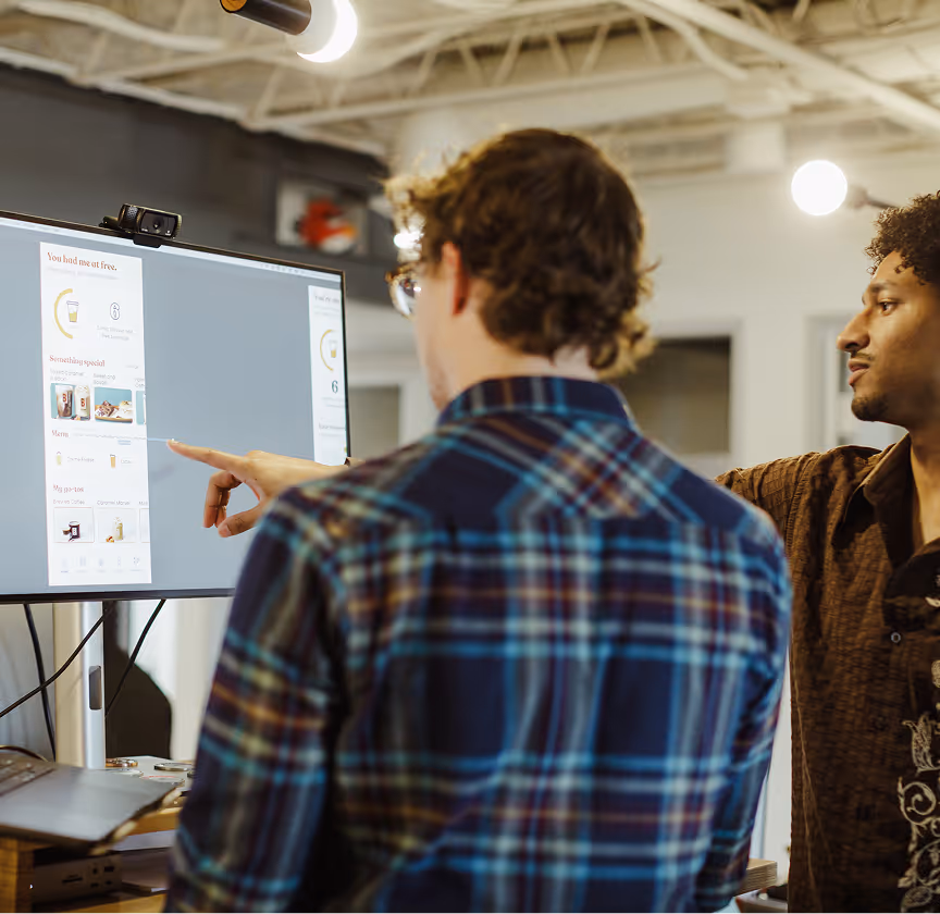 The Atomic Object team collaborates on web app development, discussing a project on their computer screen.