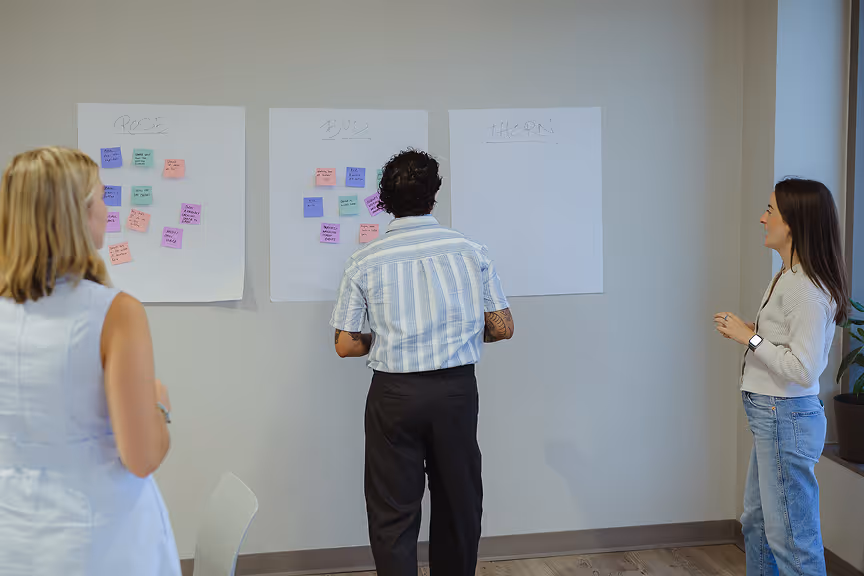 Atomic Object team collaborates using a 'Rose, Bud, Thorn' exercise with sticky notes in a meeting space.