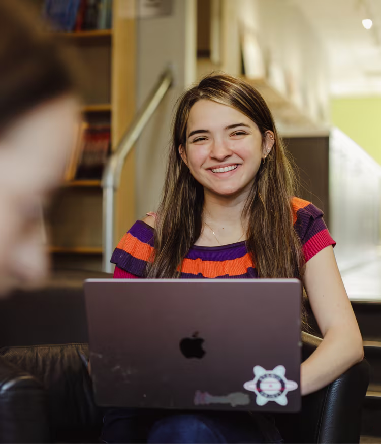 Woman smiling, while sitting at her laptop