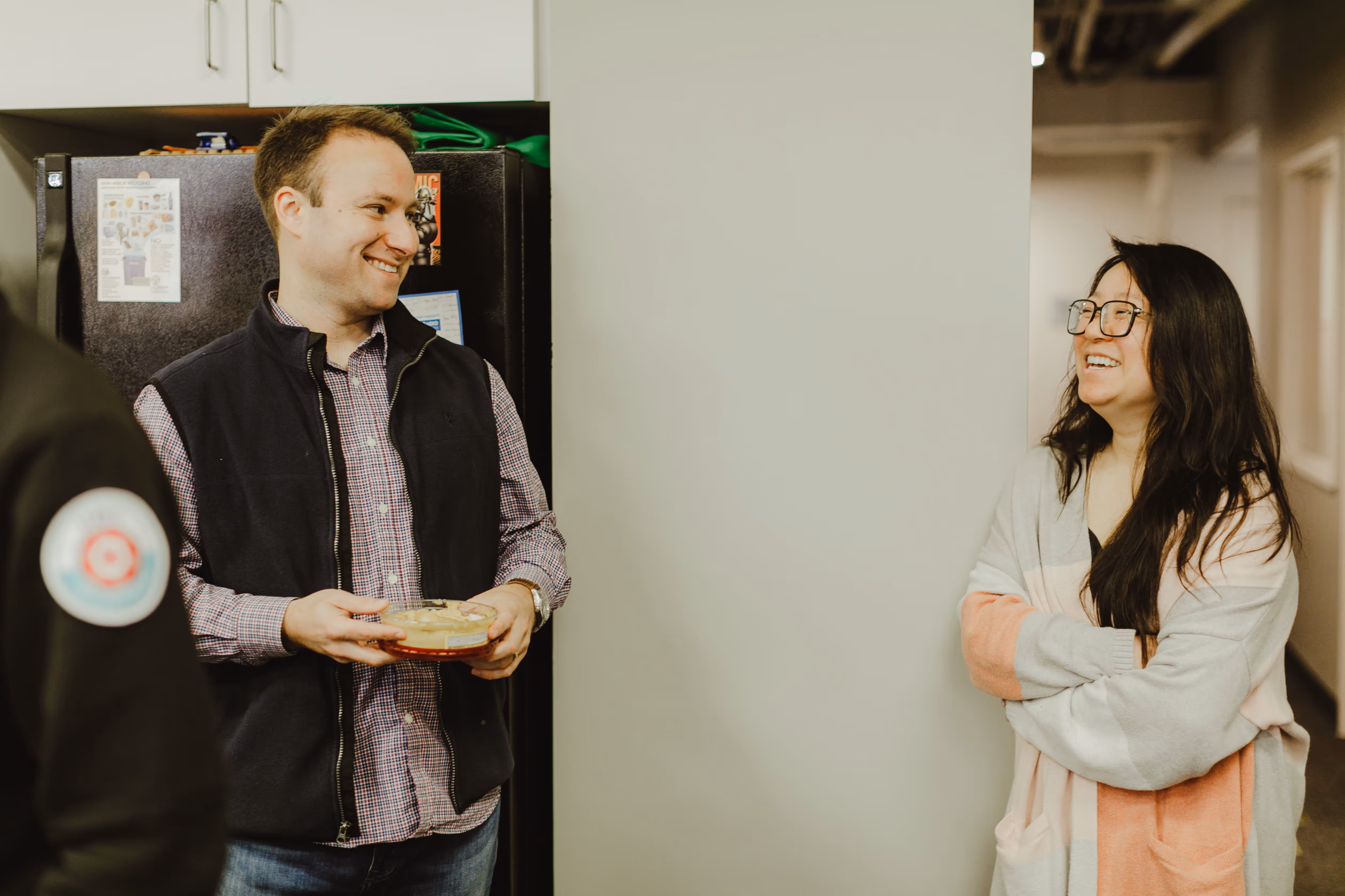 Atomic Object team members engage in a friendly conversation with snacks in a modern office setting.