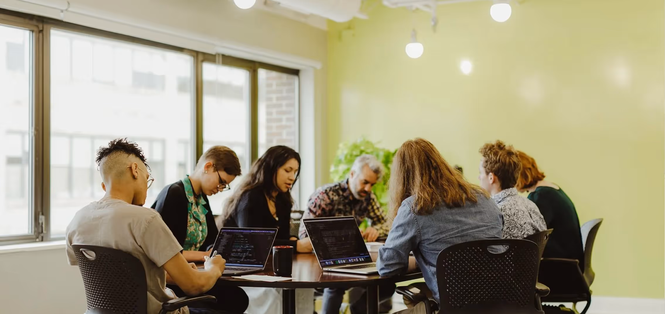 The Atomic Object team collaborates on diverse software development tasks in a vibrant office setting.