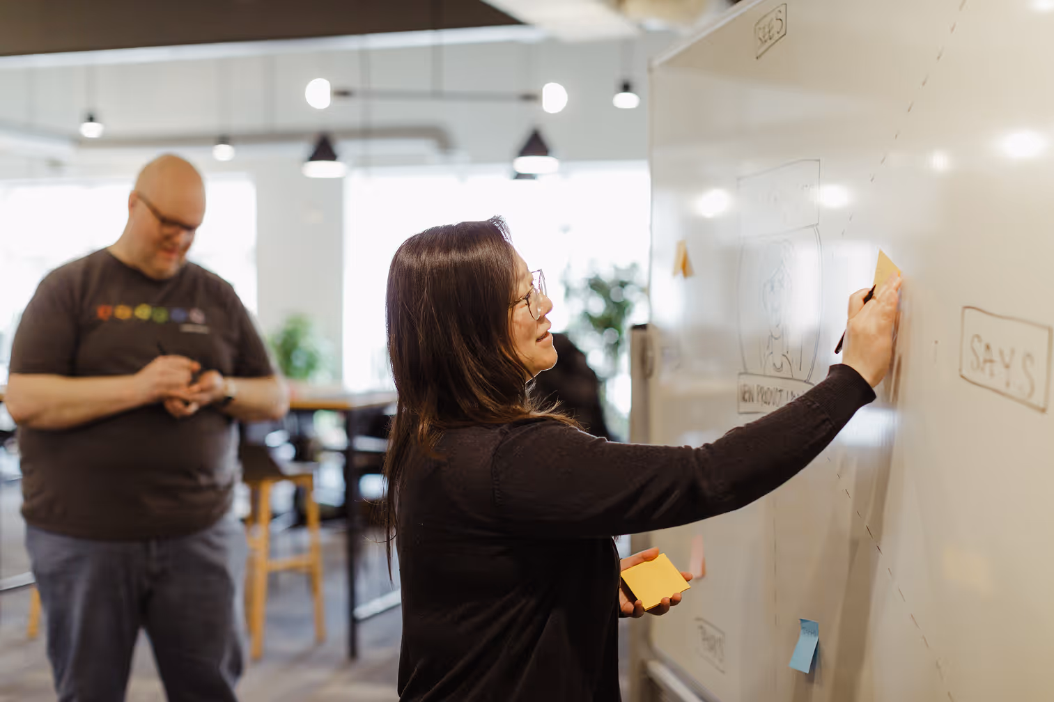 Atomic Object team members collaborate on a whiteboard, enhancing diversity and innovation in software design.