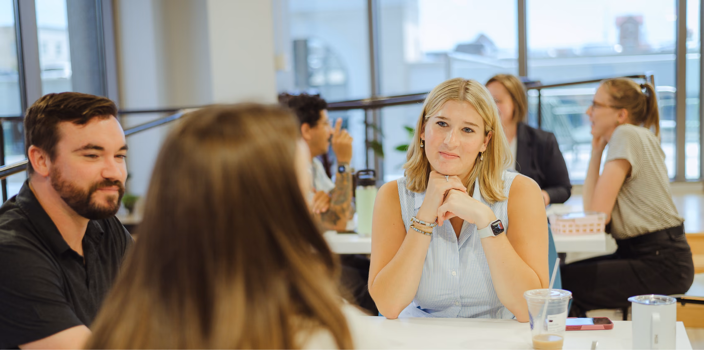 Group discussion among young professionals in an office setting, highlighting collaboration and learning