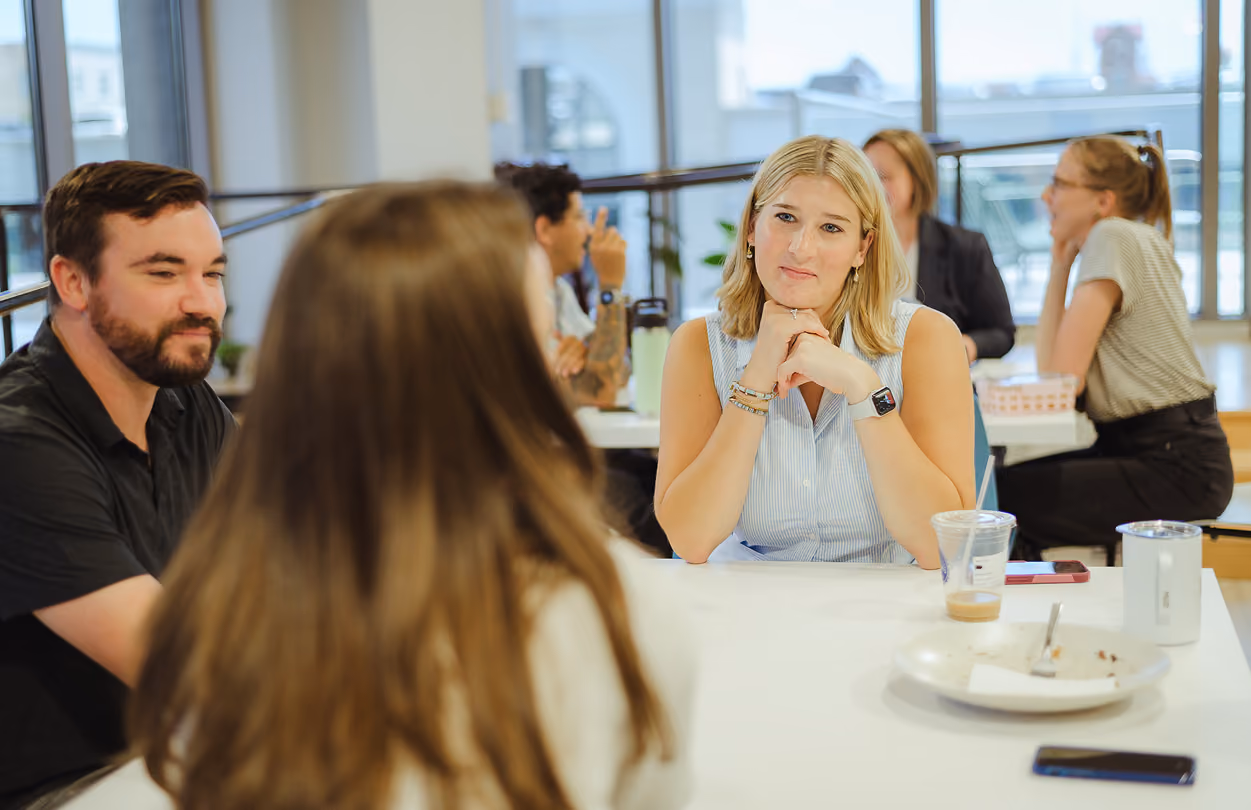 Group discussion among young professionals in an office setting, highlighting collaboration and learning