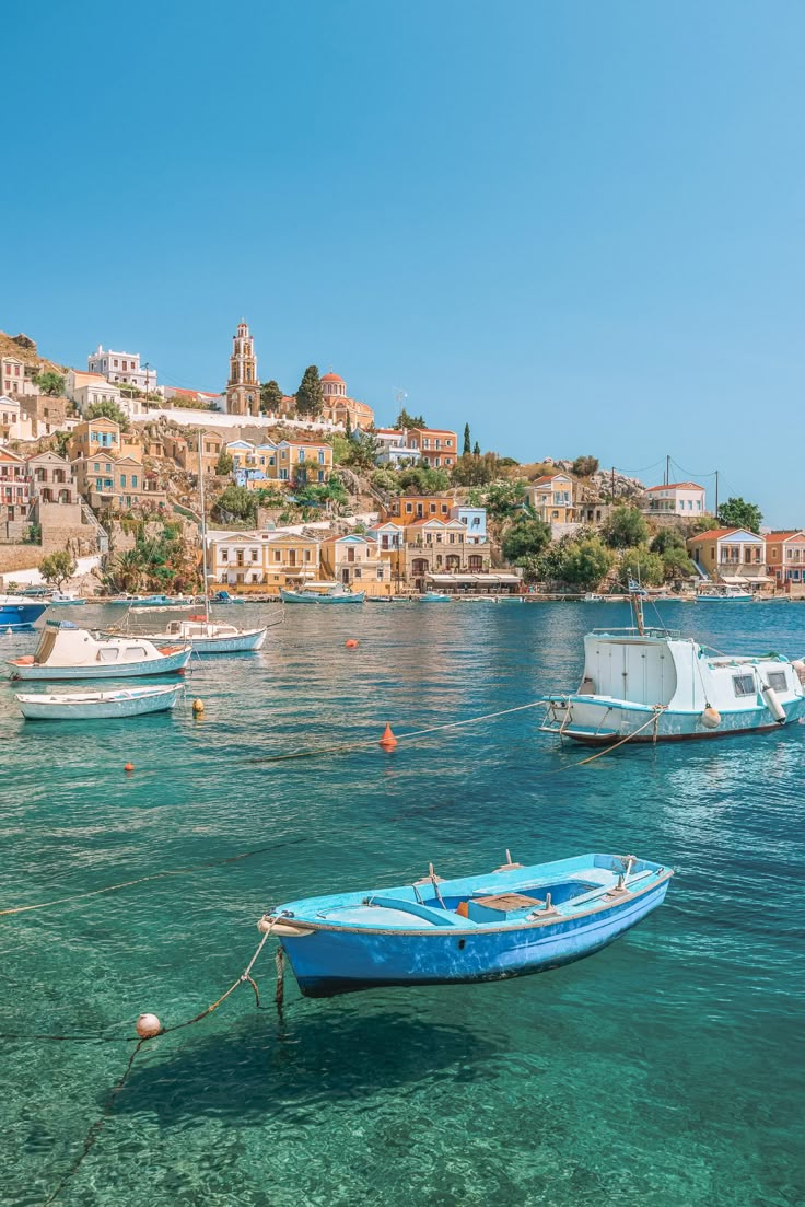 This may contain: several small boats floating in the water next to a city on top of a hill