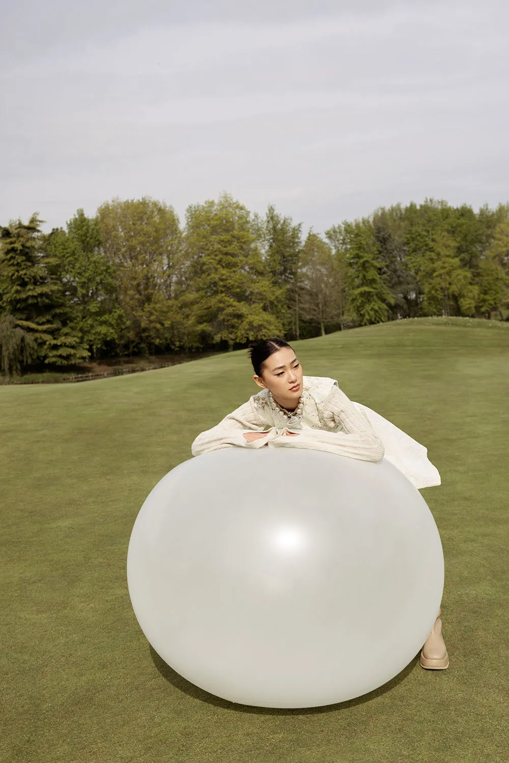 Photo éditorial mode, shooting outdoor artistique sur un golf dans les colines minimalistes avec un ballon XXL.