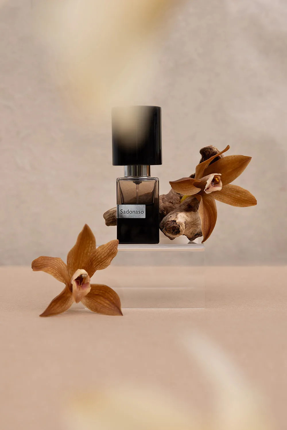 Photo commerciale still life parfum haut de gamme, mise en scène avec orchidées et éléments naturels.