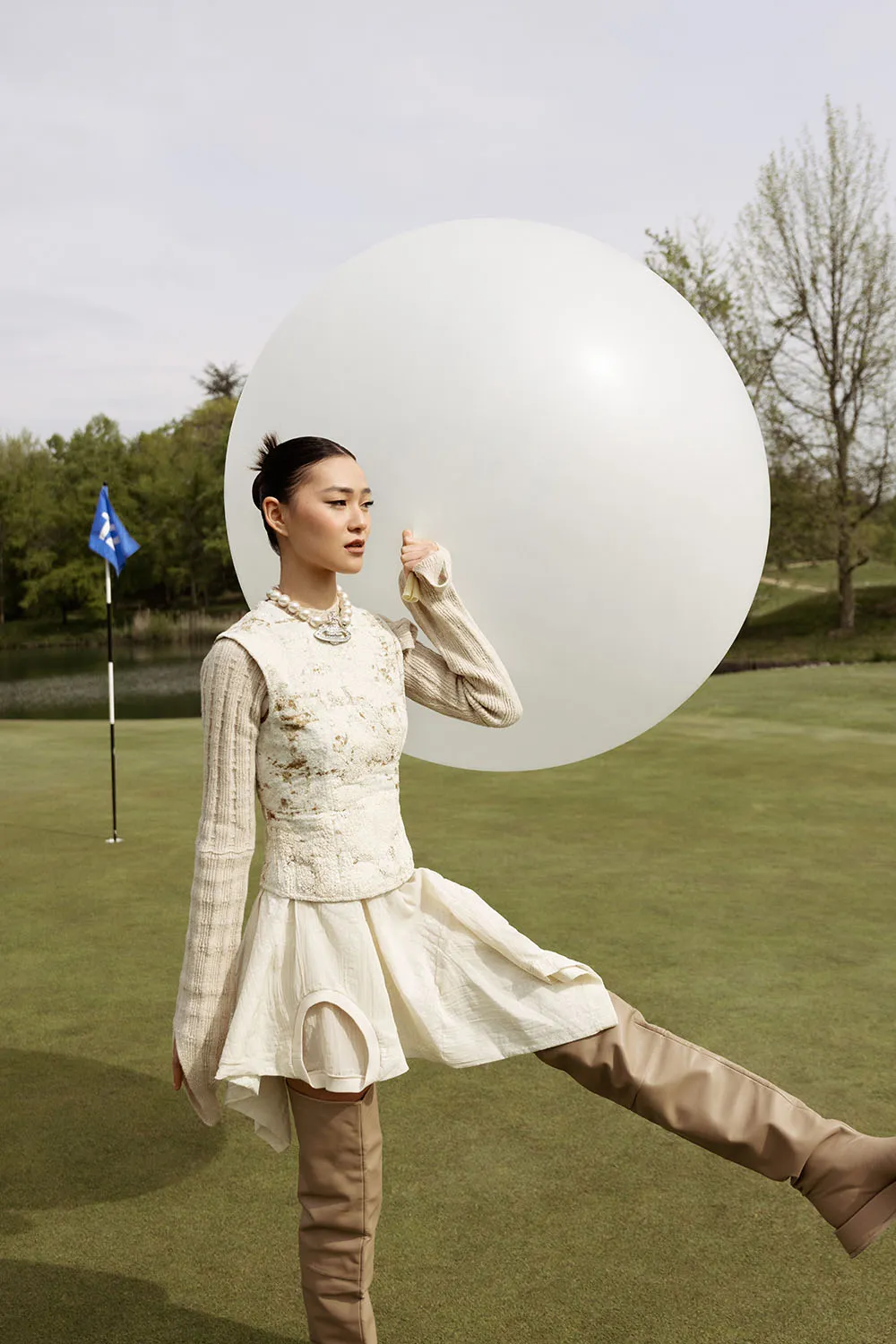 Photo éditorial mode, shooting outdoor artistique sur un golf avec un ballon XXL.