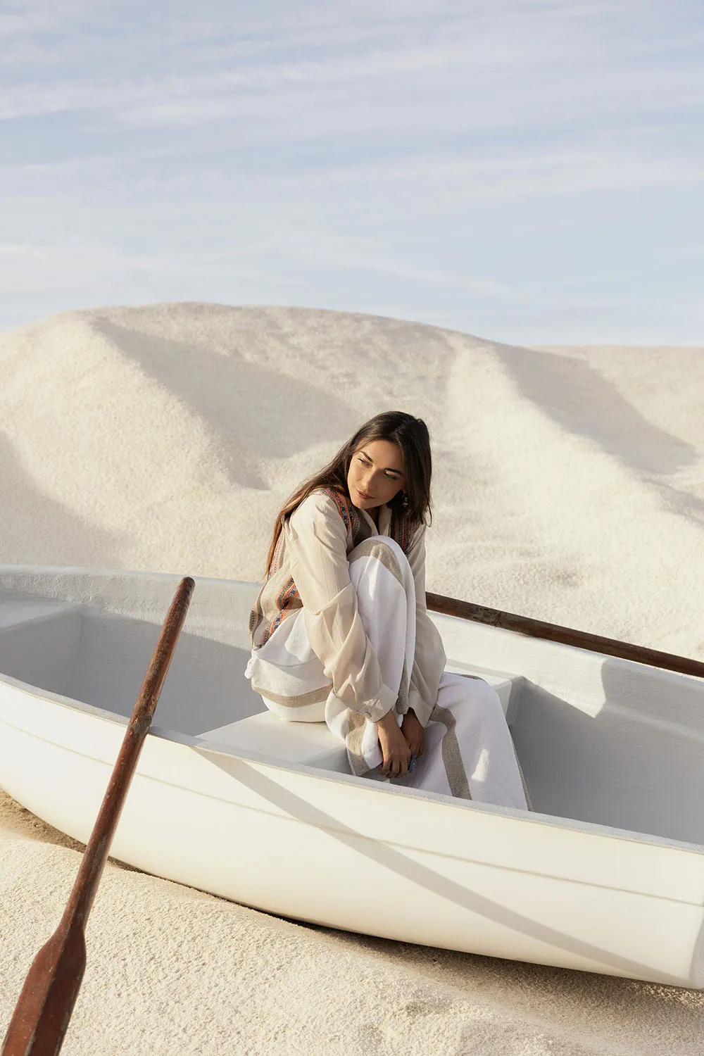 Photo éditorial mode en extérieur, shooting avec barque blanche dans un désert de sable immaculé.