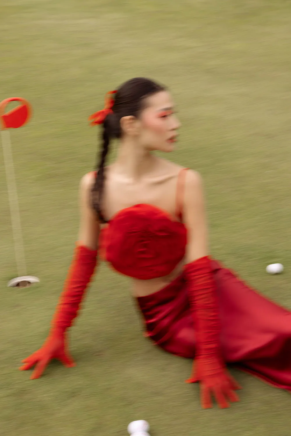 Photo éditorial mode, shooting outdoor artistique sur un golf avec un stylisme rouge.